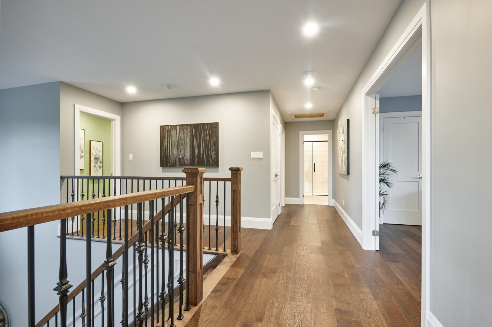 A hallway with hardwood floors and a railing.