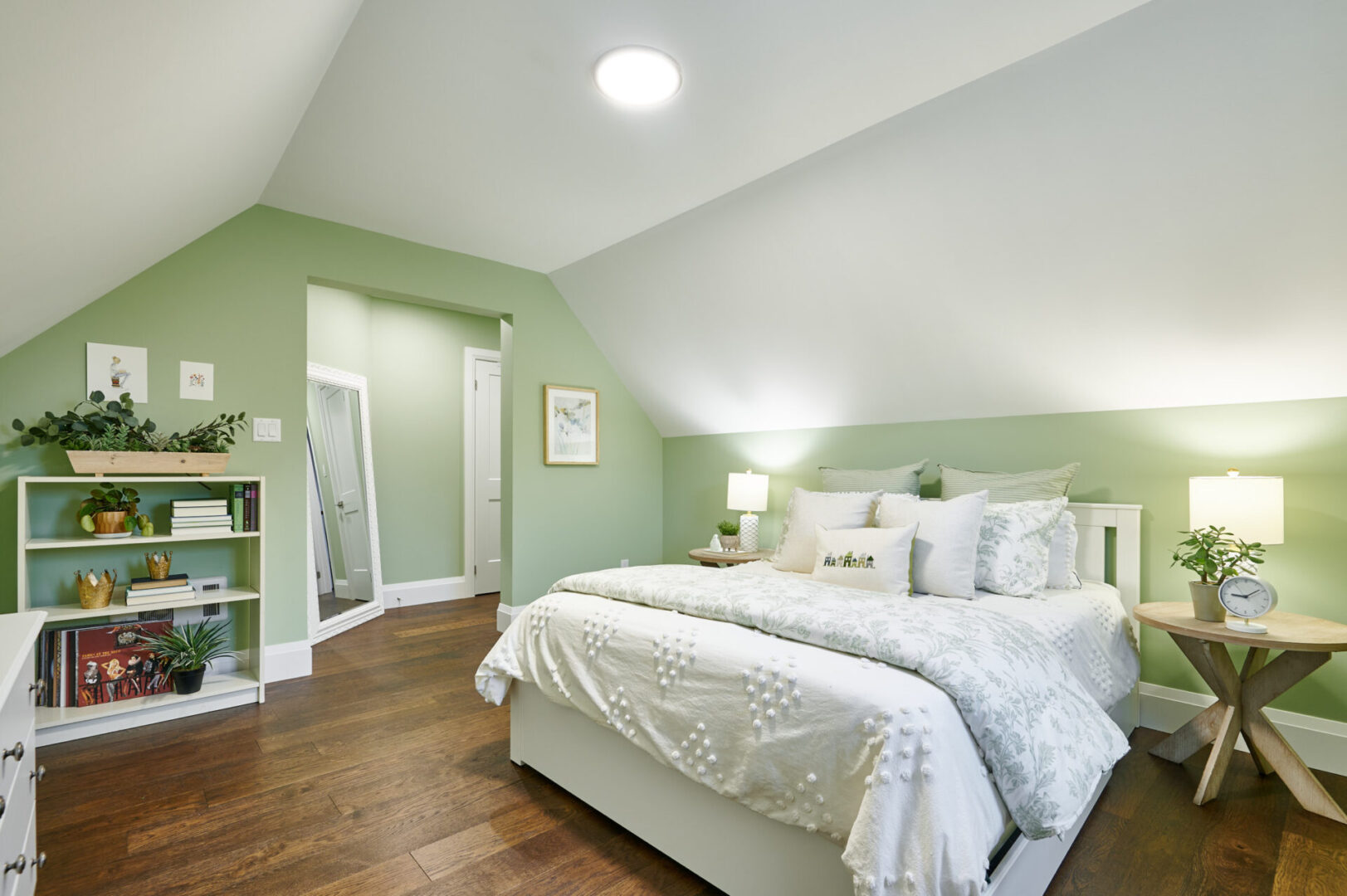 A bedroom with green walls and white bedding.